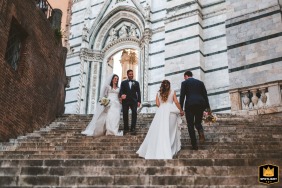 At the majestic Duomo di Siena, Tuscany, an amusing curious meeting occurs on the grand steps as one pair of newlyweds ascends while another descends, briefly crossing paths.